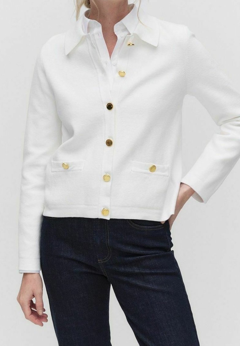 Bílé kardigan s límcem, se zlatými knoflíky a dvěma předními kapsami. Vyrobeno z hladké látky s utaženým střihem. V kombinaci s tmavými džíny.