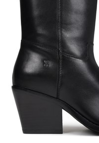 Botte de cheville en cuir noir avec une finition lisse, dotée d'un talon structuré, d'un bout arrondi et de détails en relief subtils sur le côté.