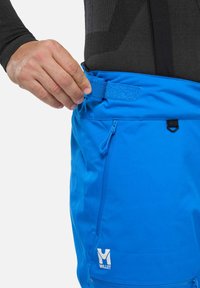 Blaue Shorts mit glatter Textur, ausgestattet mit einer Reißverschlusstasche, einem Klettverschluss am Bund und einem Logo auf der linken Seite.