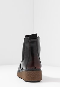 Czarne skórzane botki za kostkę z elastycznymi panelami bocznymi, o zaokrąglonym nosie, wyściełanym kołnierzem oraz teksturowaną brązową podeszwą platformową.