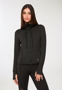 Giacca nera con zip realizzata in un tessuto morbido e elastico. Presenta un cappuccio, un cordino, due tasche frontali e aperture per il pollice nei polsini.