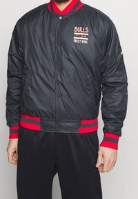 Sort bomberjakke med røde accenter. Har broderet tekst "BULLS" og "SWEET HOME", trykknaplukning og sidelommer.