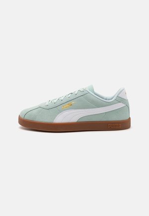 Lysegrøn ruskind Puma sneaker med hvid sidestribe, brun sål og gyldent Puma-logo på siden og tungen, set fra ydersiden.