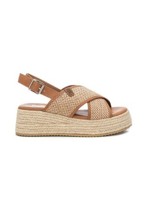 Sandal de esparto tejido en tono beige con tira trasera, que incluye una plataforma de yute trenzado y una plantilla de cuero suave para mayor comodidad.