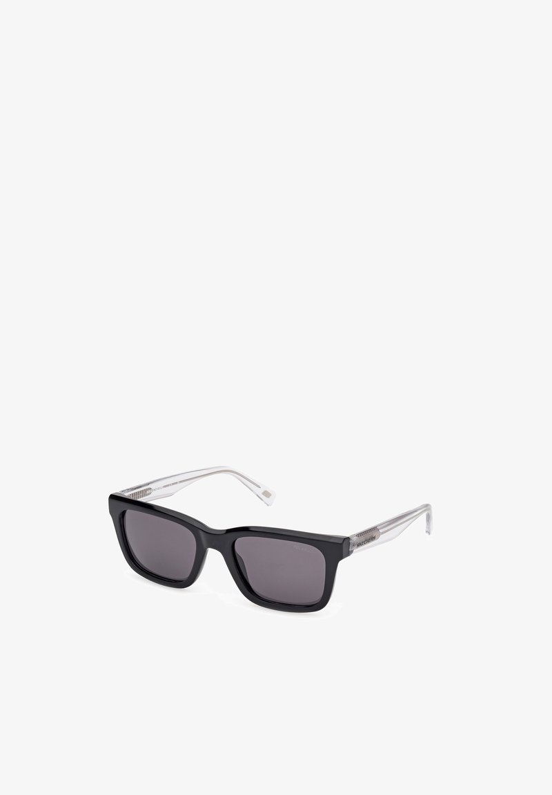 Gafas de sol negras en forma rectangular con lentes oscuros. Patillas curvas y transparentes con acentos metálicos. Acabado suave, diseño minimalista.