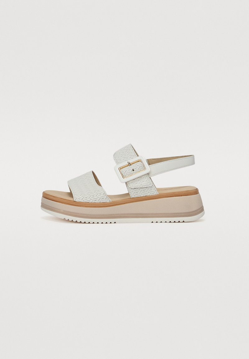 White wedge sandals with a textured upper, two adjustable straps, and a buckle detail. Thick platform sole with a contrasting brown accent.