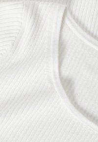 Ribbat vitt tyg med en slät, rundad necklinje som visar en fin textur och subtil lyster, lämplig för vardagsbruk.