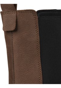 Brown leather and black fabric merge in a structured design, featuring visible stitching and a side tab for grip or closure.