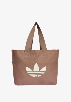 Sac cabas en tissu marron avec de larges anses et un grand logo trèfle blanc d'Adidas au centre avant.