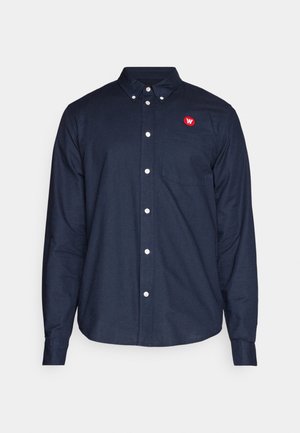 Navy blue long-sleeve button-up shirt made of fabric with a smooth texture, featuring a red logo on the chest and a front pocket.