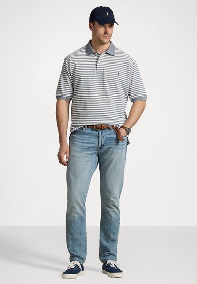 Stripet polo skjorte i marineblå og hvit, blå jeans og marineblå caps. Funksjoner inkluderer kortermede armer og klassisk krage. Uformelt fottøy.