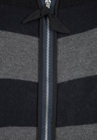 Stickad cardigan med grå och marinblå horisontella ränder. Har en full dragkedja, kontrasterande ribbad hals och tygband i detalj vid kragen.