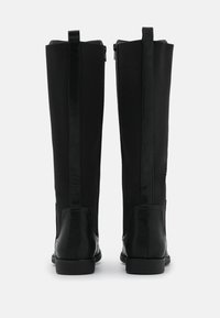 Botas negras hasta la rodilla con un diseño elegante, hechas de una combinación de tela y cuero con una textura suave y punta redondeada.