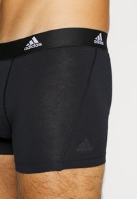 Svarta Adidas kalsonger med bred elastisk midjeband som har en vit logo. Slät textur och en åtsittande design för komfort.