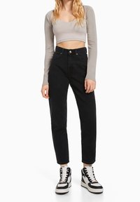 Svarta hög midjas jeans med raka ben, kombinerat med en åtsittande grå långärmad tröja och svartvita sneakers, minimalistisk design.