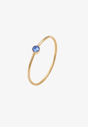 Anillo de oro con una banda delgada que presenta una sola piedra azul redonda en el centro. Acabado suave, diseño minimalista.