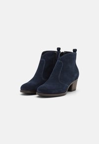 Botines de ante azul marino con una forma curvada, que cuentan con cremalleras laterales, costuras en contraste y un tacón bajo y apilado.