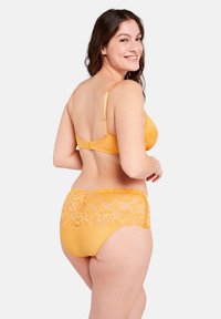 Set di lingerie giallo con un design in pizzo floreale sul retro, spalline regolabili e una forma liscia e aderente.