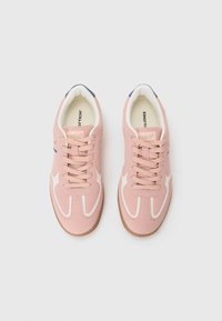 Adidași din suede roz cu accente albe, având vârf rotund, șireturi plate și o talpă din cauciuc maro. Interiorul are un călcâi contrastant de culoare albastru închis.