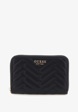 Billetera de cuero negro con patrón de espiga acolchado, logotipo en tono dorado "GUESS EST 1981" en el frente, cierre con cremallera alrededor, forma rectangular.