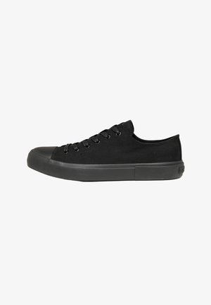 Sneaker in tela nera bassa con suola in gomma nera, puntale e lacci neri mostrata di profilo su sfondo bianco.