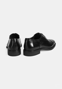 Zwarte leren dresschoenen met een gladde afwerking, ronde neus en vetersluiting. Voorzien van een gegomde buitenzool met structuur voor grip.