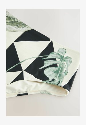 Čierna a krémová látka s geometrickým vzorom a zelenými tropickými listami, hladká textúra s priliehavým lemovaním a kontrastnými farbami.