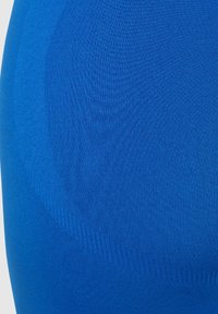 Blått åtsittande tyg med en slät textur. Materialet har en lätt lyster och horisontell ribbstruktur. Designen framhäver kroppens konturer.
