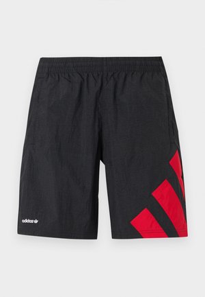Schwarze Sportshorts mit roten diagonalen Streifen auf der linken Seite, elastischem Bund, hergestellt aus leichtem, strukturiertem Stoff. Adidas-Logo sichtbar.