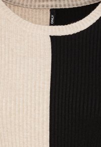 Top a maglia a coste con design a blocchi di colore nei toni beige e nero, scollatura rotonda e tessuto testurizzato. Etichetta del marchio visibile sul retro.