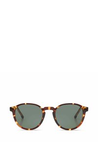 Lunettes de soleil en écaille de tortue avec des verres verts, de forme ronde et des accents clairs contrastants. Elles disposent d'un pont robuste et de branches élégantes.