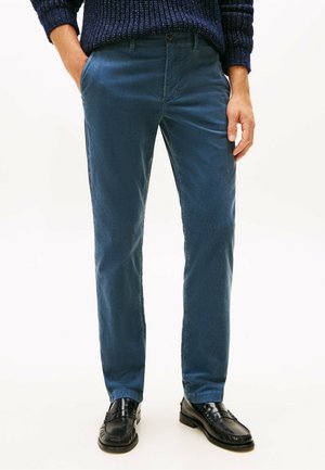 Chinos in cotone blu con taglio dritto, dotati di tasche laterali e chiusura con bottone. Abbinati a mocassini neri per un look curato.