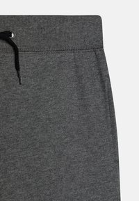 Grå joggebukser med en myk tekstur, elastisk midje med snøring, og synlige sømdetaljer.