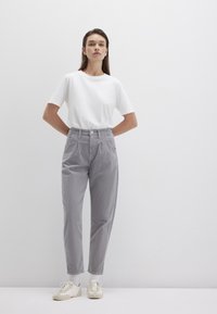 Weißes kurzärmliges T-Shirt kombiniert mit hellgrauen, karierten, hoch taillierten Hosen, die über vordere Falten und slip-on Sneaker in hellen Farben verfügen.
