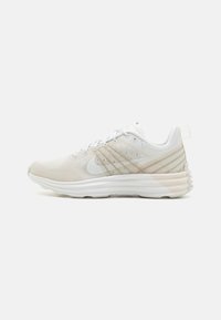 Scarpa da corsa leggera in mesh bianco e beige chiaro, caratterizzata da una suola ammortizzata, design con lacci e sottili strisce decorative sulla parte superiore.