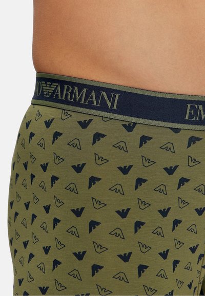 Olive green boxer briefs with a navy waistband featuring the "Armani" logo. The fabric displays a repeating pattern of small, dark logos.