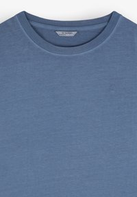 Tricou albastru cu guler rotund, fabricat dintr-un material moale, având un logo subtil brodat pe piept. Textură netedă și o croială clasică.