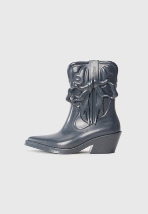 Gray glossy ankle boot with pointed toe, decorative bow detail, and curved block heel; features textured design on upper.