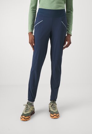 Navy lightweight trousers with a high waistband, featuring two zippered side pockets and elastic cuffs. Made from breathable stretch fabric.