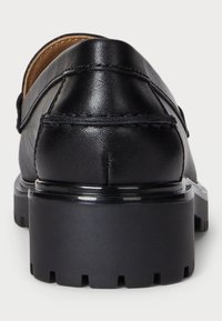 Črne usnjene loafer čevlje z gladko površino, zaokroženim nosom in debelim gumijastim podplatom s teksturiranim oprijemnim vzorcem. Šivani detajli ob šivih.