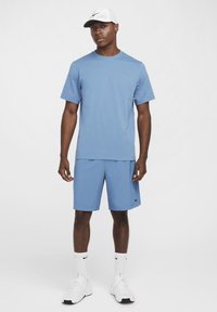 Light blue athletic t-shirt and shorts made of smooth fabric. White Nike cap and sneakers. Classic fit with logo accents. White socks.