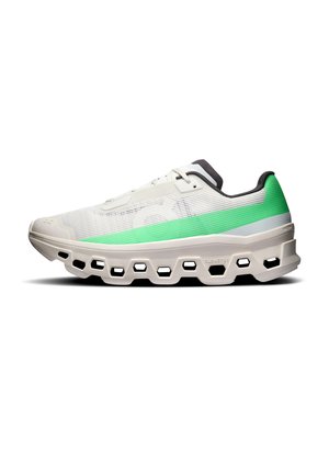 Weißer Sneaker mit grünem Verlauf an der Ferse, schwarzem Innenfutter und dicker Sohle mit sechseckigen Aussparungen, seitlich gesehen.