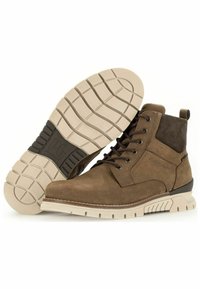 Botas de tobillo de ante marrón con un upper texturizado, acento de ante oscuro en contraste y una suela de goma clara con un patrón de superficie.