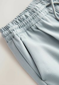 Helle blaue Shorts aus weichem Stoff mit einem elastischen Bund und Kordelzug. Sie verfügen über Seitentaschen und eine strukturierte Oberfläche.