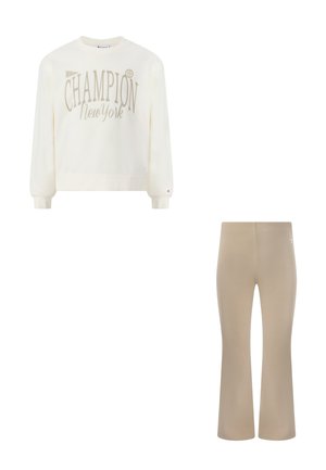 Felpa bianca a maniche lunghe con scritta "Champion New York", abbinata a pantaloni beige a zampa d'elefante, entrambi capi di abbigliamento casual.