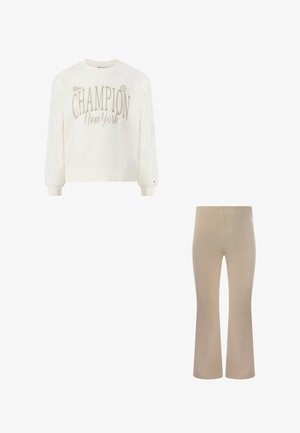 Biała bluza z długim rękawem z napisem "Champion New York", w połączeniu z beżowymi rozszerzanymi spodniami, oba elementy casualowej garderoby.