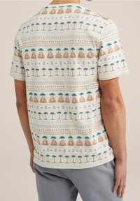 Koszula z krótkim rękawem na jasnobeżowym tle, z kolorowym wzorem palm, gór oraz geometrycznych kształtów w odcieniach pomarańczowego i zielonego.