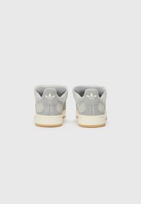 Gray suede sneakers with a white rubber sole and cream accents, featuring a padded collar and a minimal logo on the heel.