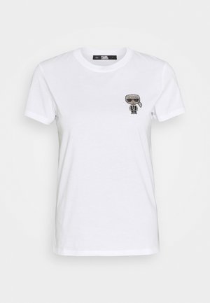 Wit T-shirt met korte mouwen en ronde hals, met een klein zwart-wit cartoonfiguurtje met zonnebril op de linkerborst.