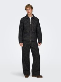 Veste en denim foncé et pantalon à jambes larges avec coutures contrastantes, dotés de poches avant et d'une fermeture zippée. Design en tissu texturé.